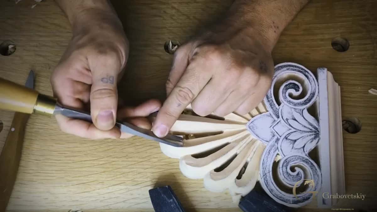 Both hands steering a long gouge along one leaf