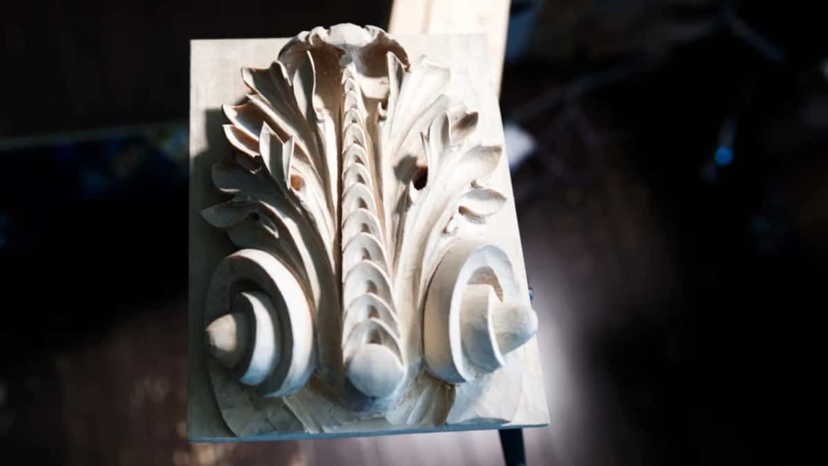 Dark background behind the finished carving, deep shadow under every leaf