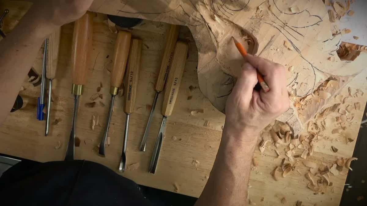 An orange pencil draws a fresh line across the carved surface