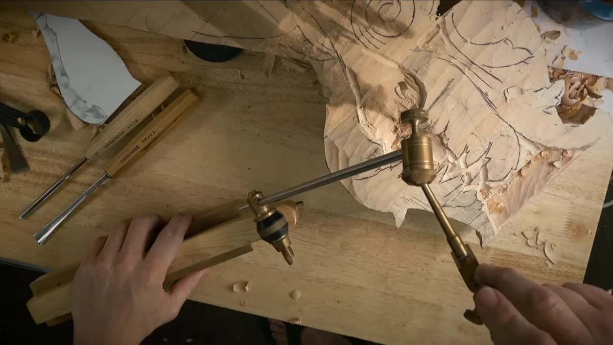 Brass pointing machine resting on a wood bar, its needle held by hand over the hollow