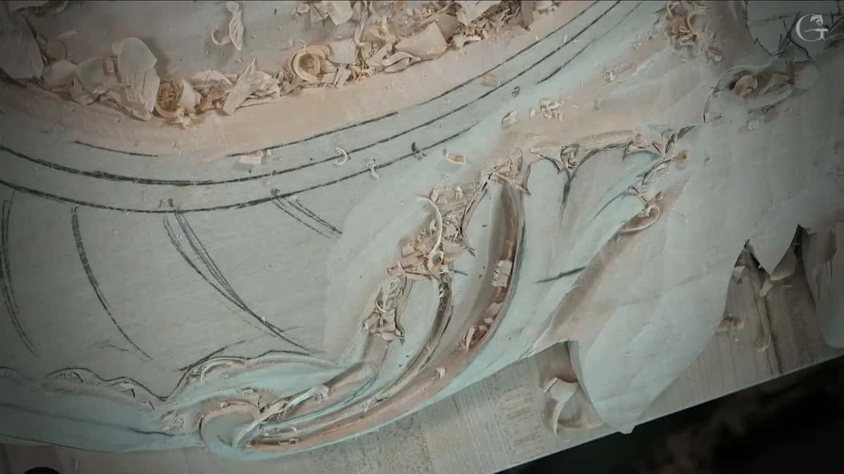 The carved leaf with nobody touching it, deep grooves running down into a round curl at the bottom