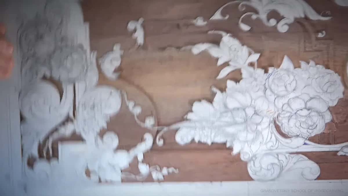 Carved roses and scrolling leaves, pale against a brown ground