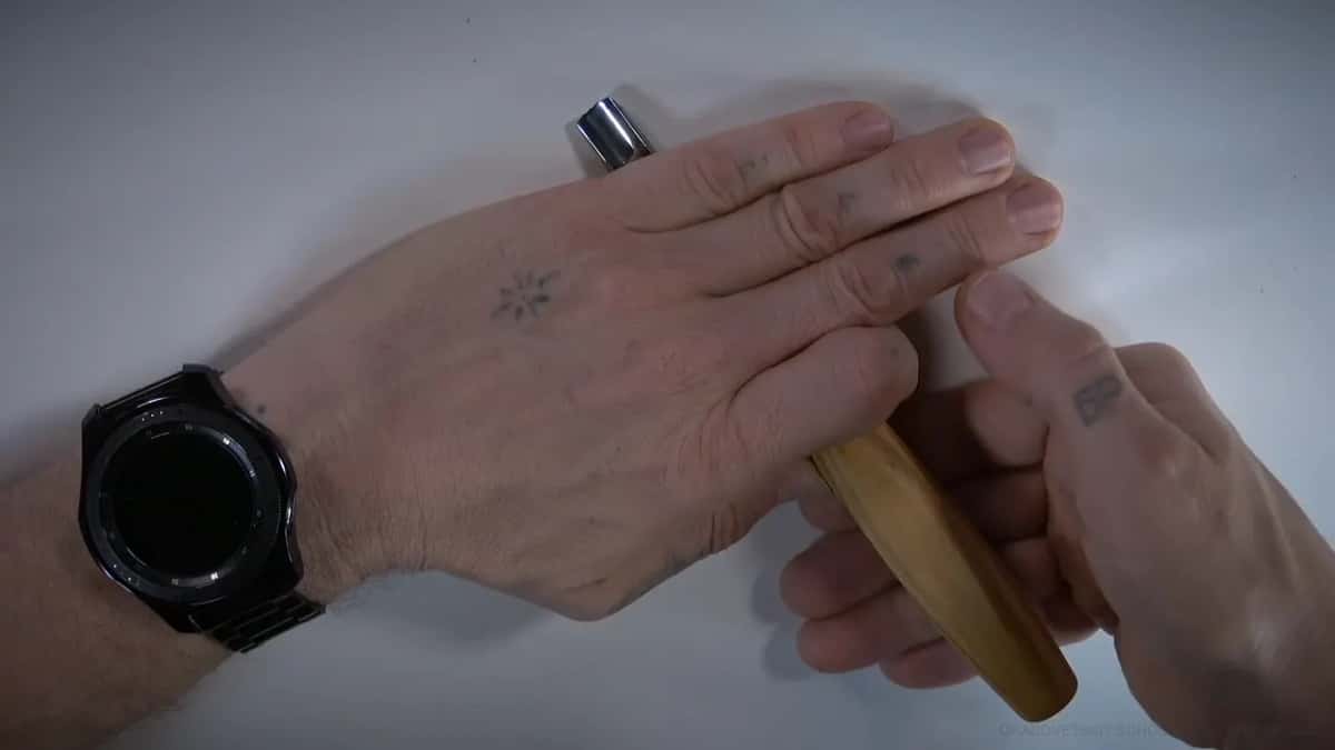 One hand flat on top of a pale handle, a watch on the wrist