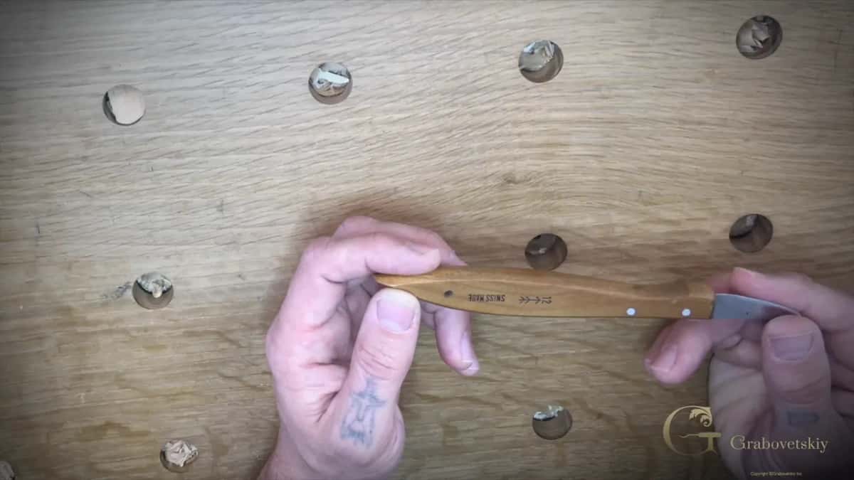 Marking stamped along the handle of the knife, held flat in both hands over the bench