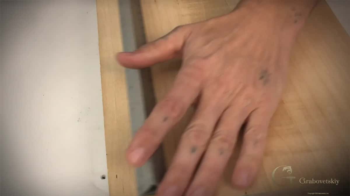Hand flat on the board beside a metal ruler