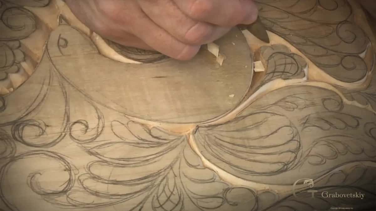 Fingers at the top of the bird, knife in hand, two pale chips curling up beside them