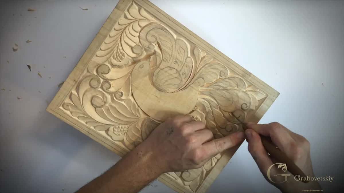 Both hands low on the right, aiming the knife at one feather