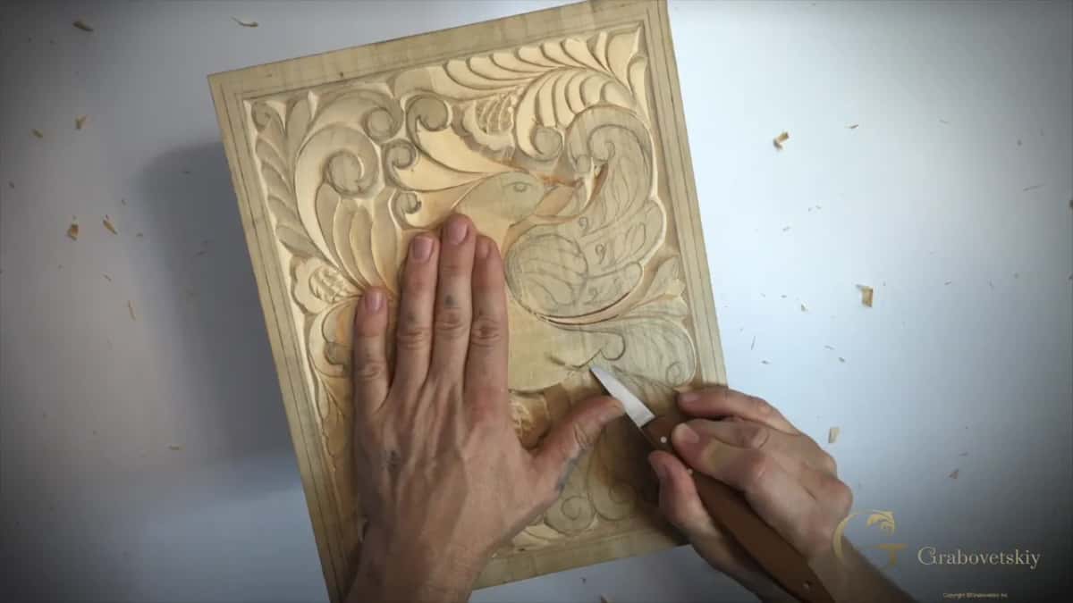 Left hand flat on the bird, blade at the right of its body