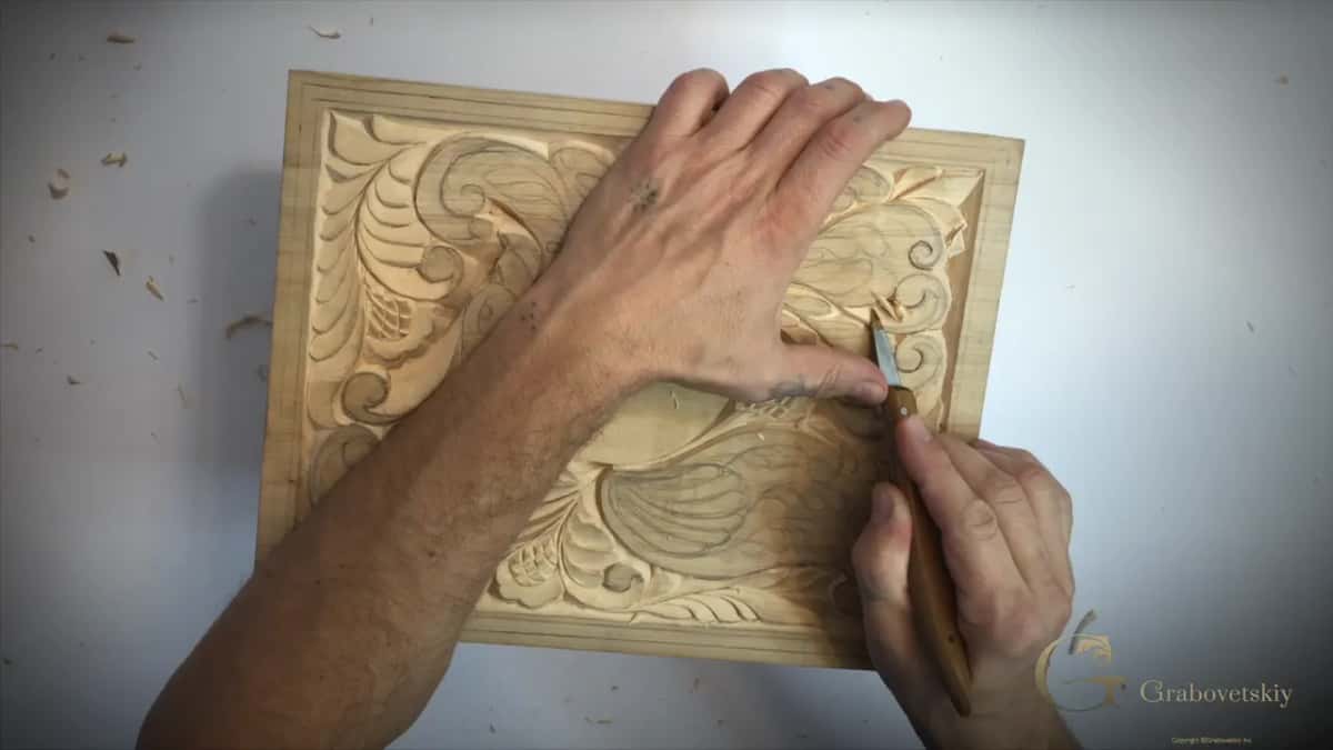 Board square to the camera with my left palm across its top and the knife upright near the middle