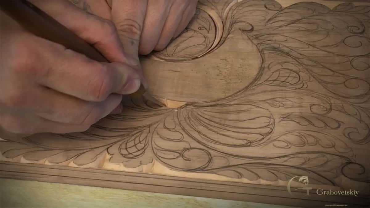 Two hands guide the knife along a curve below the round flower.