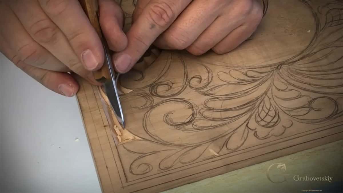 Both hands on one knife, the blade upright in a curl near the left border.