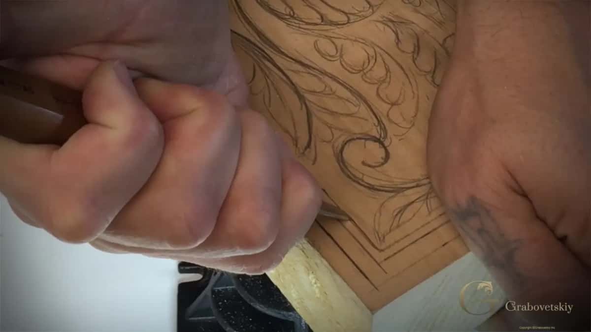 Fist on the handle at the corner of the board, a black vise jaw below.