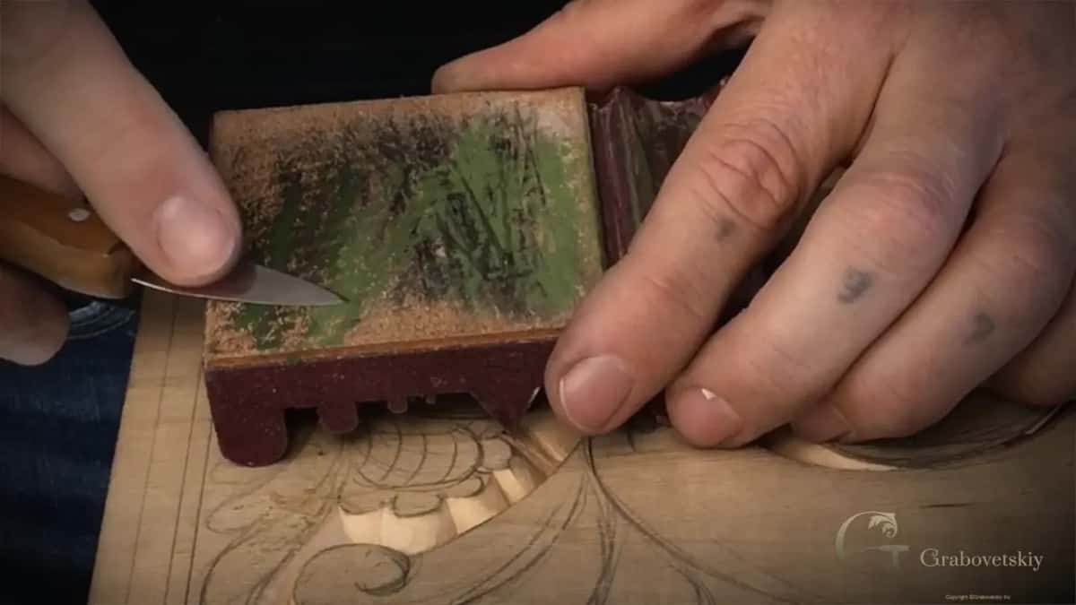 Knife blade laid flat across the green leather, the handle at the left of the frame.