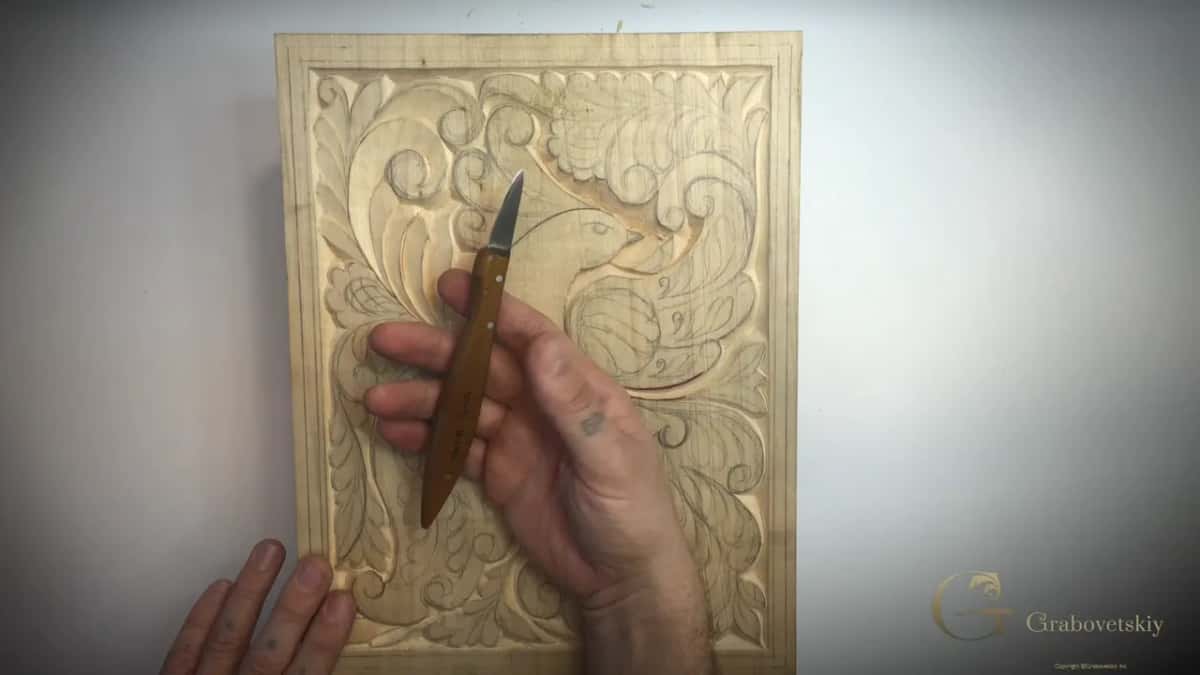 A short knife held up over the carved bird of paradise panel