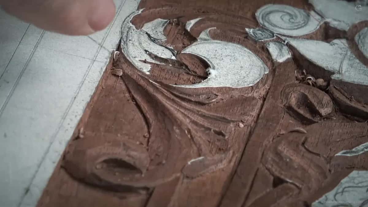 Close and low, side light across carved walnut with scraps of paper