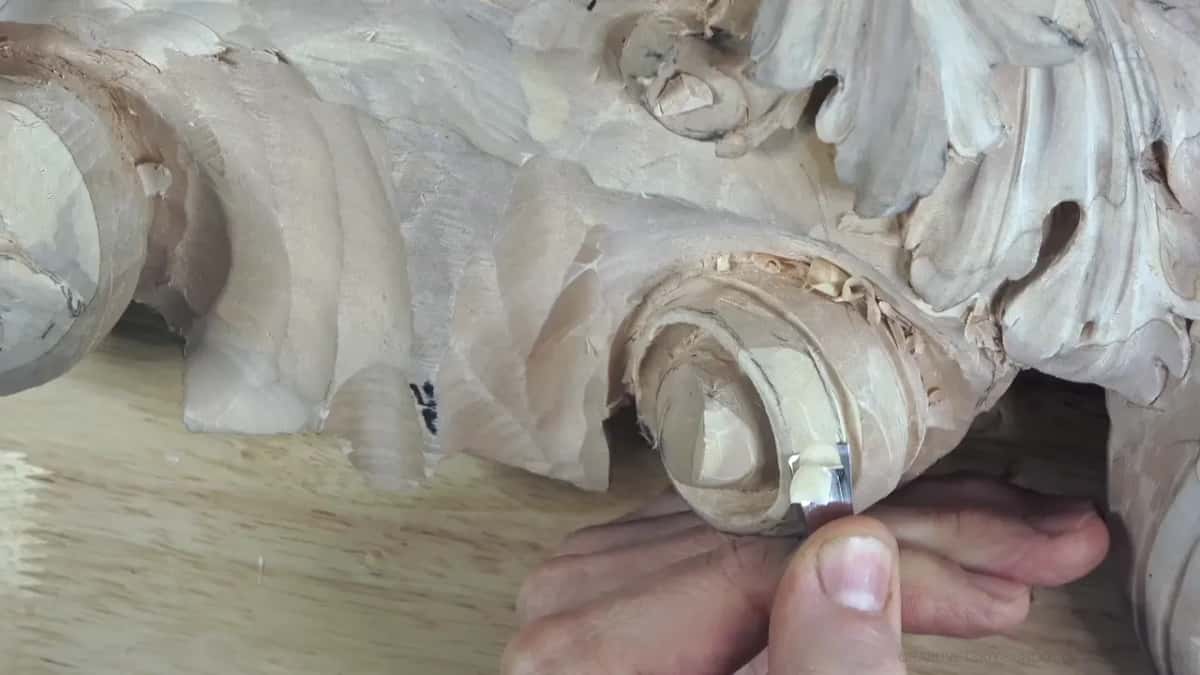The thumb braces a short flat blade at the bottom right, the fingers curled beneath it.
