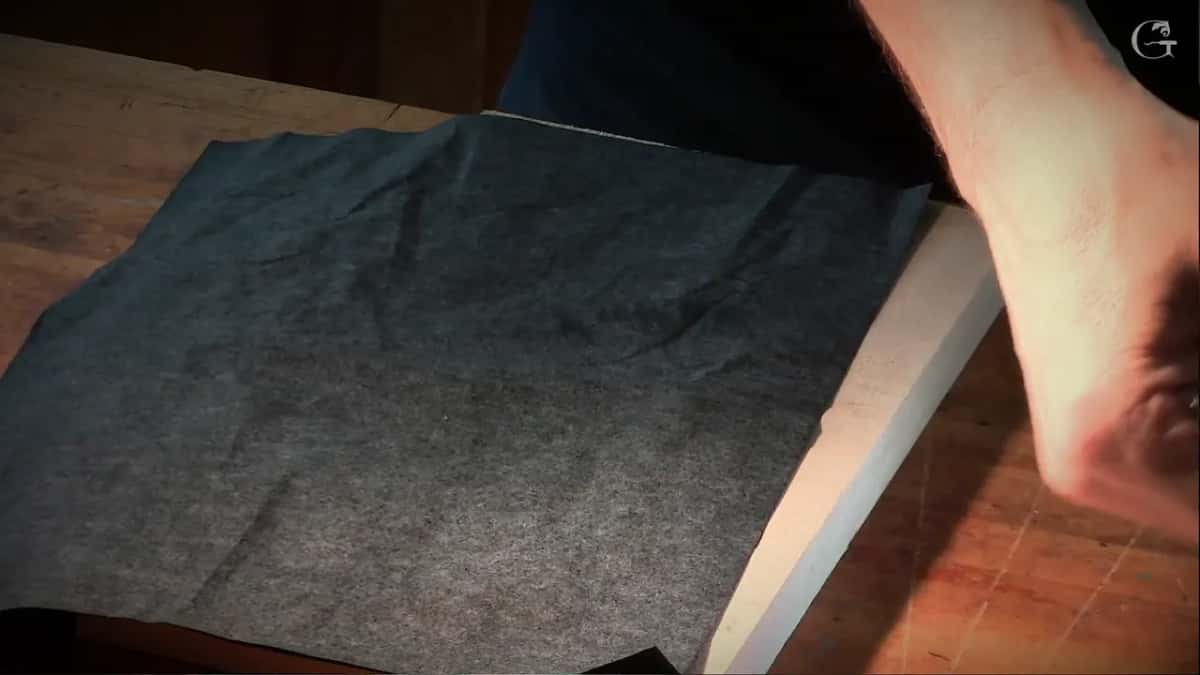 Carbon paper laid on the board, a hand pressing at its right side