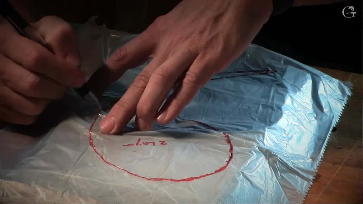 A pen following the red outline on the plastic, the words 2 layer written inside it