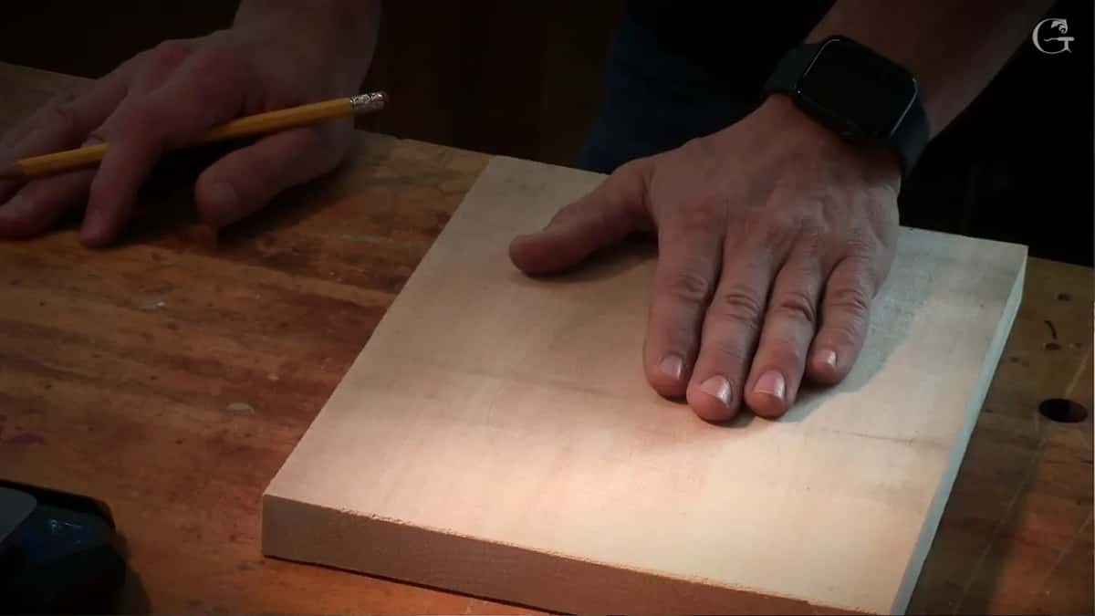 Bare board under a flat hand, a pencil held ready in the other