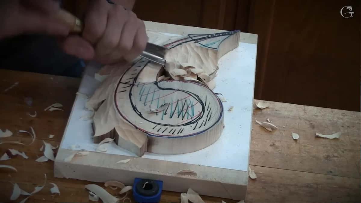 Where the scroll meets the upper leaves, a gouge at work among the chips