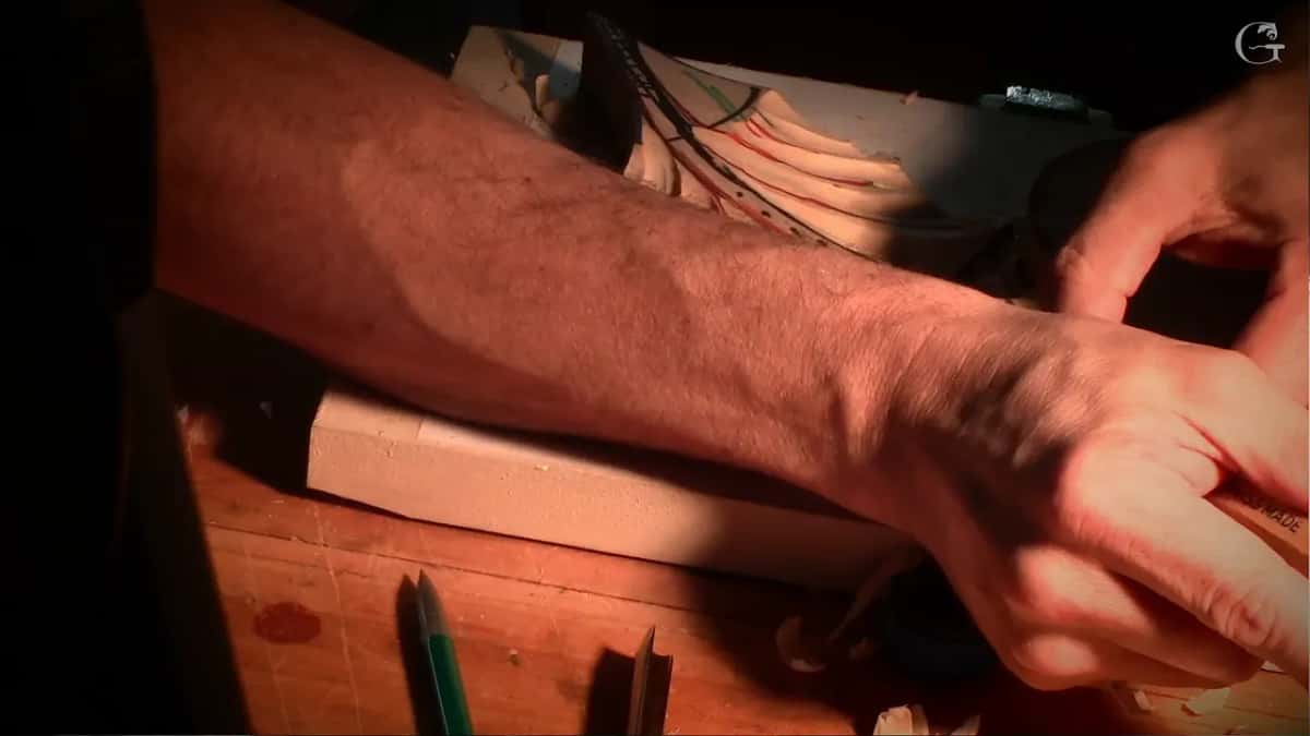 Forearm across the frame as he reaches over the work