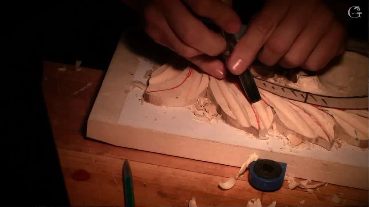 Two hands steer a gouge into a leaf