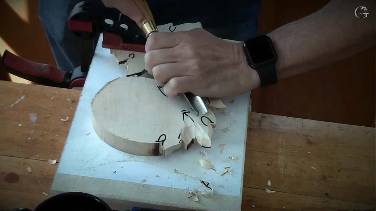 Gouge working along one leaf beside a black arrow, the clamp holding the far end