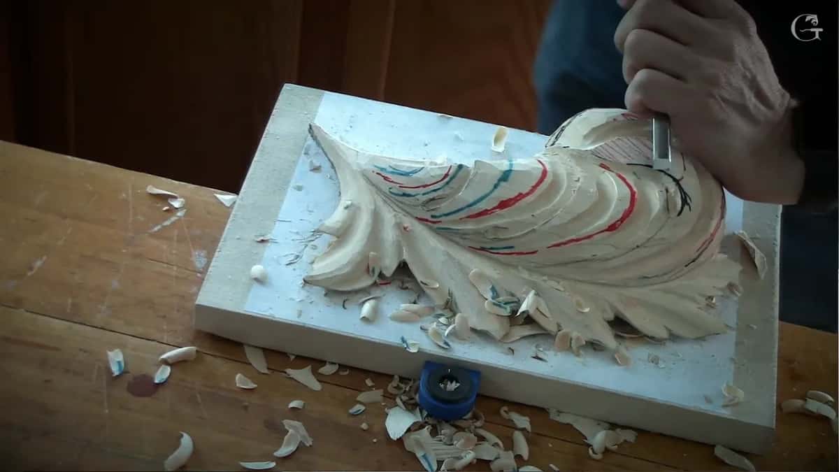 Shavings pile up while a gouge works the upper corner of the leaf