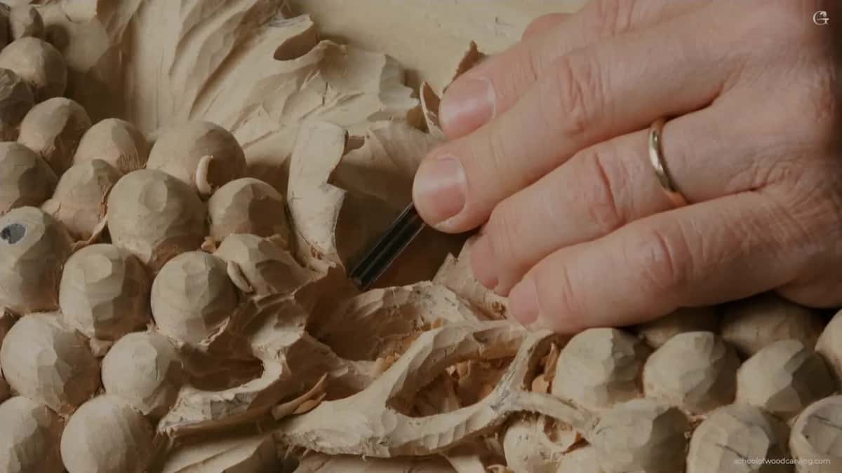 Fingers guide a narrow blade between rough grapes and a twisting stem