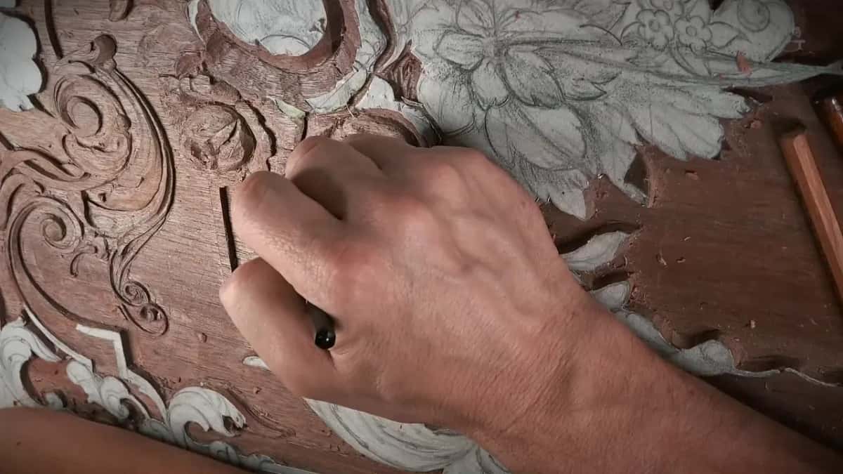 Closed hand on the panel, with the black end of a tool handle showing between the fingers