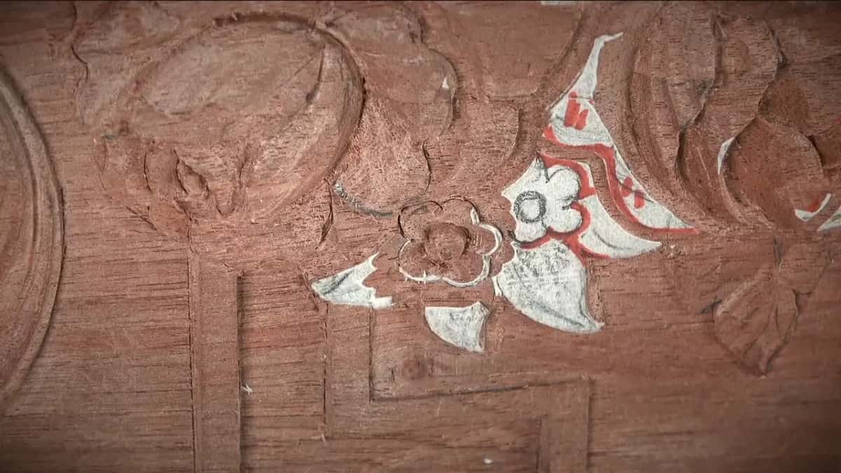 From above, one carved flower sits beside a second that is still covered in red and white paper
