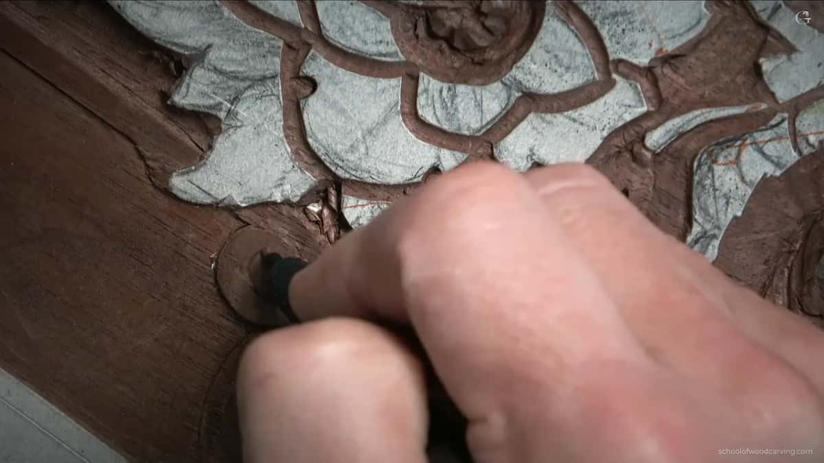 A pencil in his fist, redrawing the line of the volute after the first carving