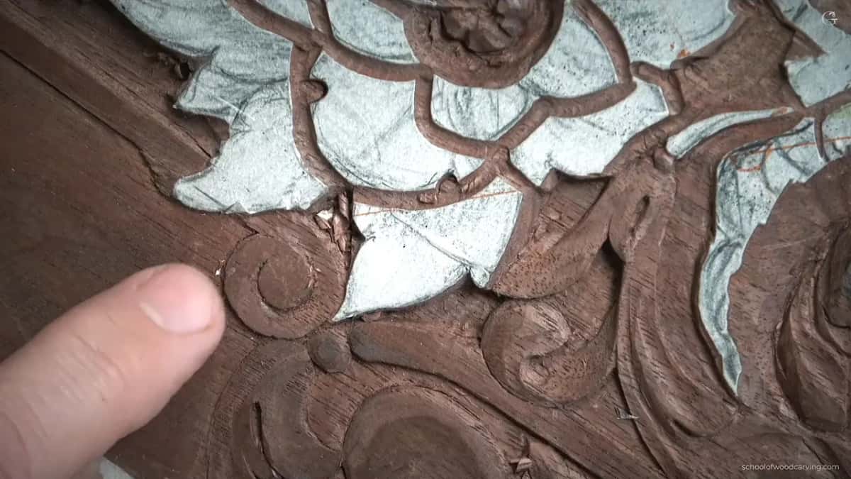 Thumb pointing at the carved volute