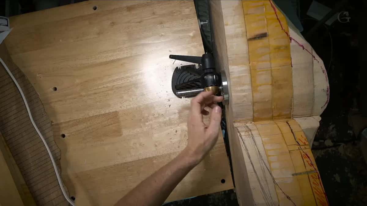 A hand grips the black vise mechanism below the bench top, the big block beside it