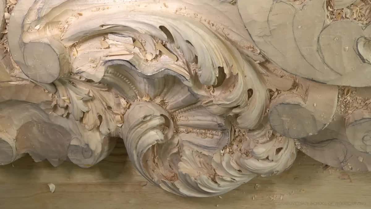 Top view of the carved shell with the big acanthus scrolls curling around it and chips on the bench.