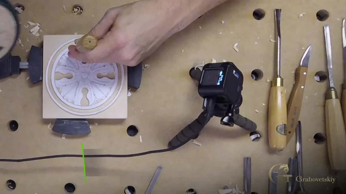 From above, the clamped block sits beside a small camera on a tripod, with gouges laid out to the right.