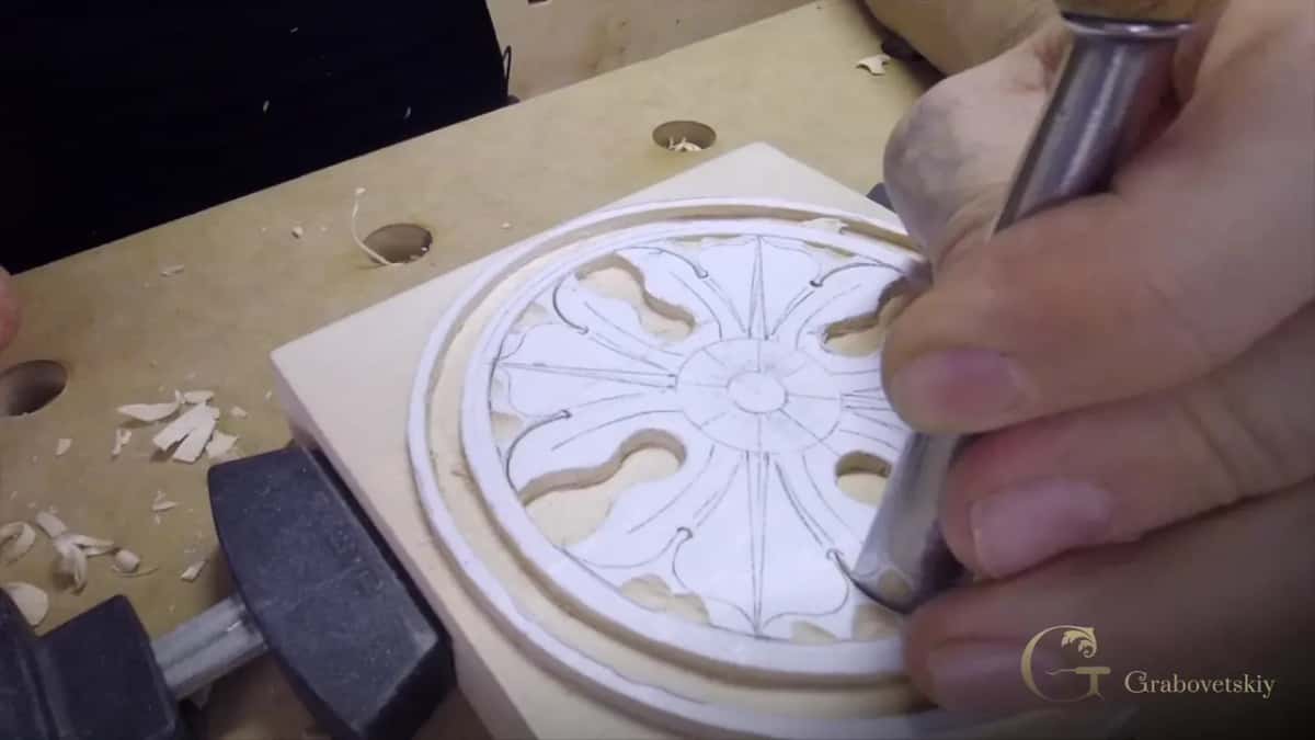 Fingers wrapped low on the steel, right next to the edge, while the tip works a petal near the ring.
