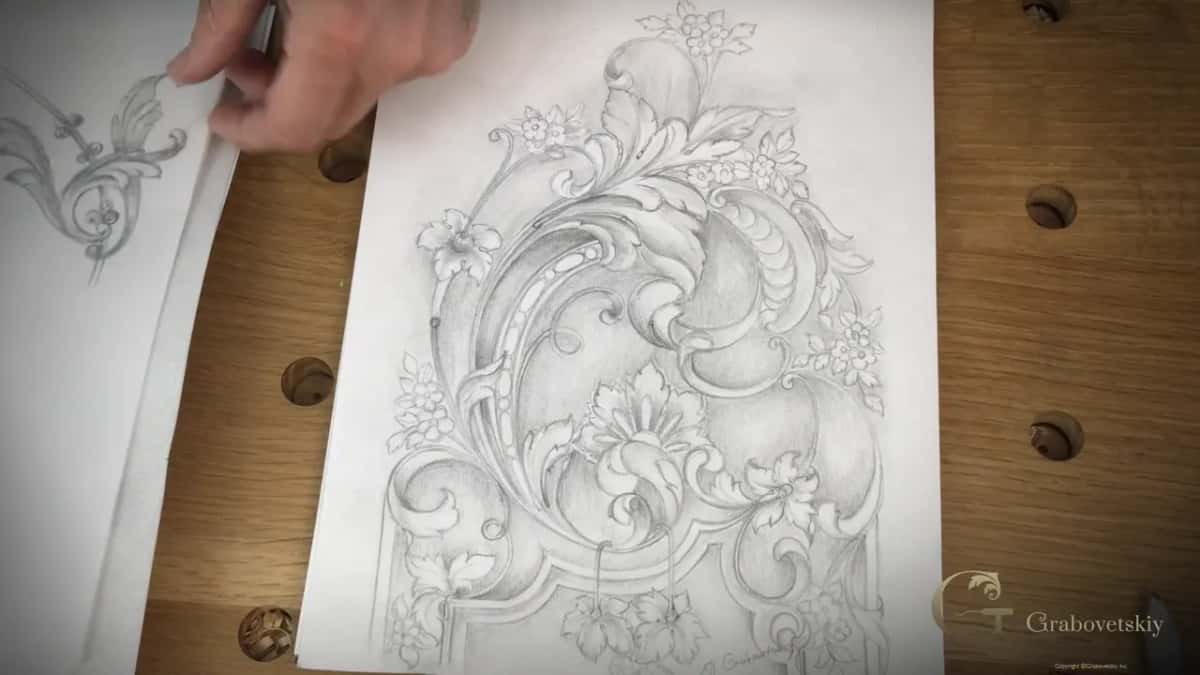 Fingers lift one sheet off a pile of acanthus scroll drawings