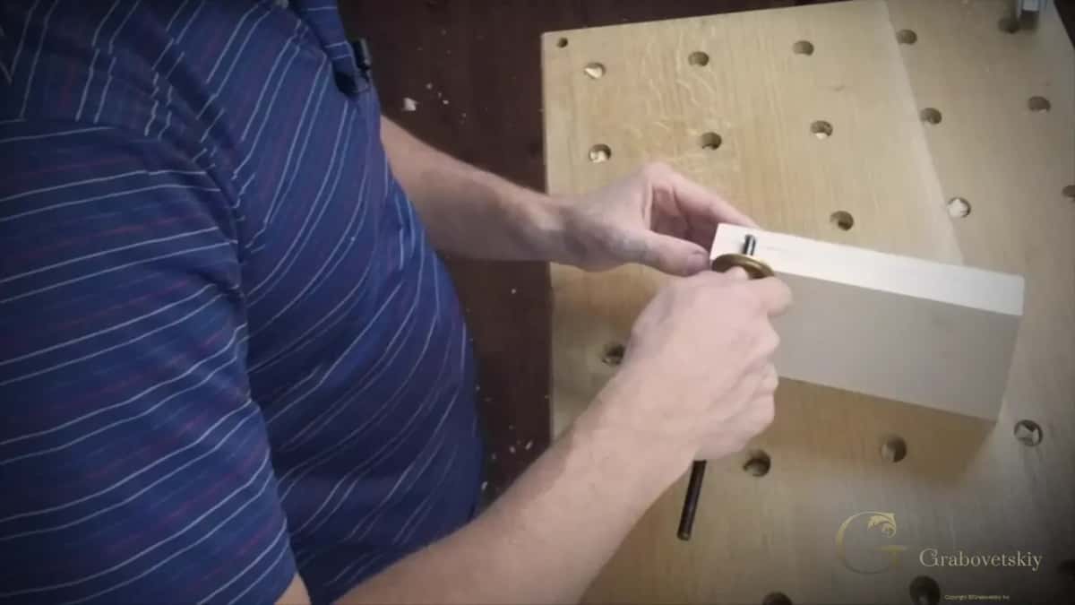 A marking gauge held against the edge of the block, its brass head turned toward the camera