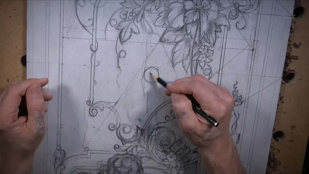 Pencil drawing a small circle on the paper pattern, his left hand open beside it