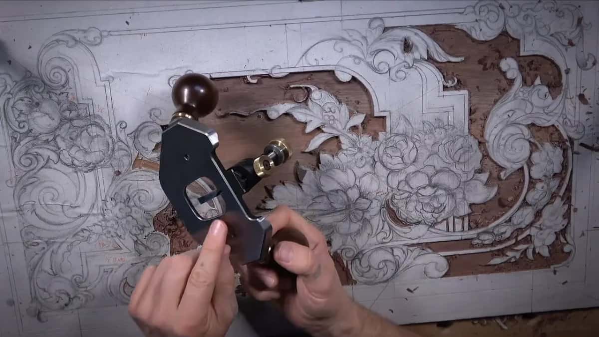 Two hands on the router plane, one by its brass knob
