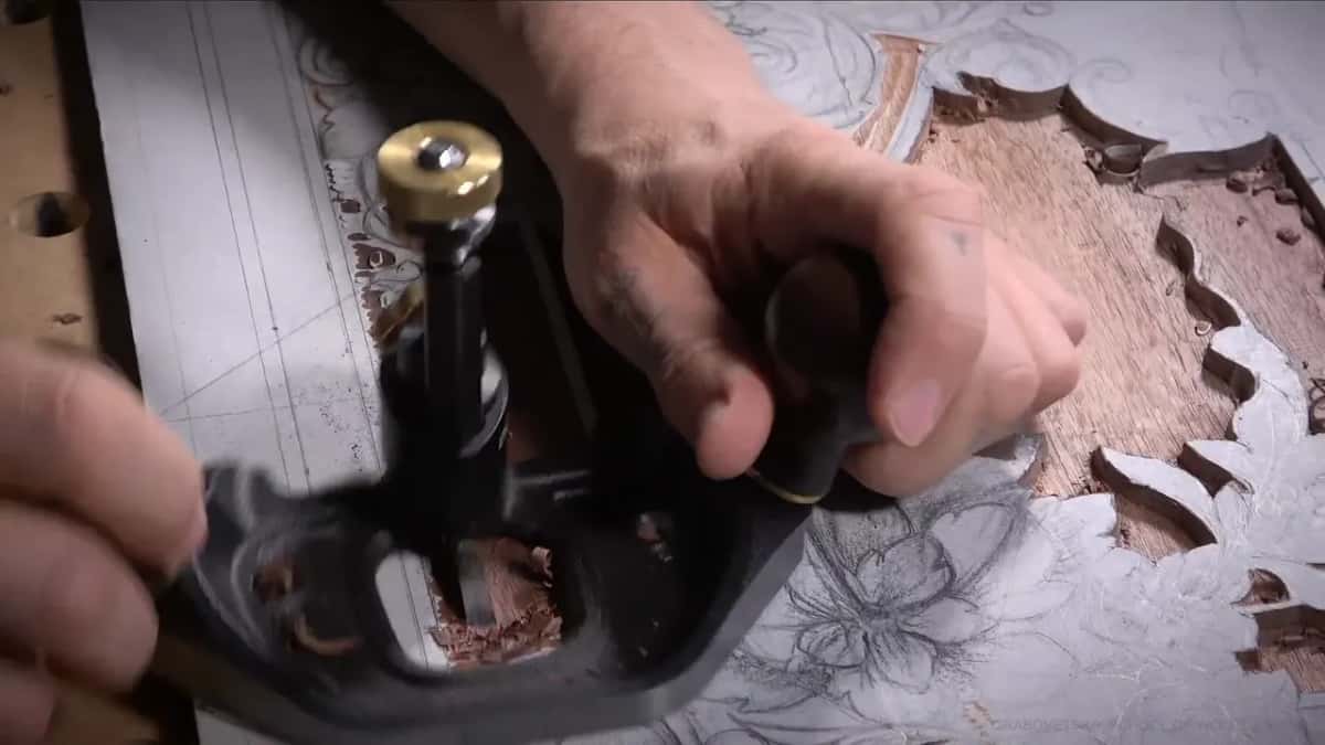 Hands pushing the router plane beside the paper-covered flowers
