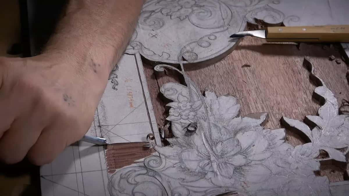 Working a gouge along the narrow strip at the left edge, a knife lying near the top