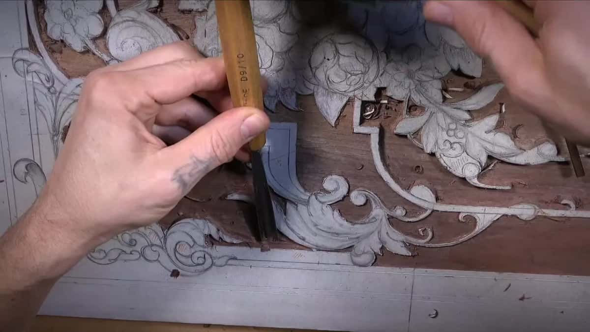 A gouge stamped D9/10 held upright beside the scroll, a second hand at the top