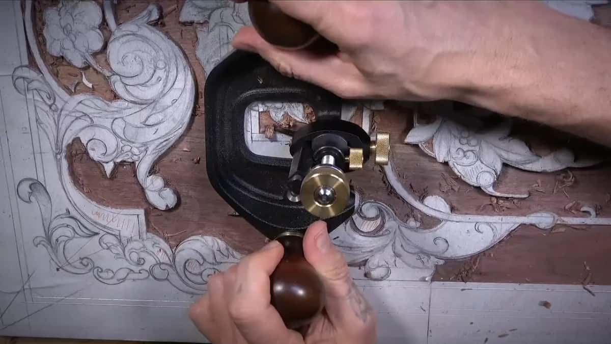 Both hands on the knobs of the router plane, the ground below it partly cleared