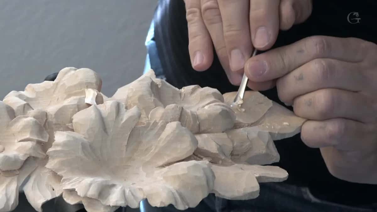 Both hands guide one small tool into the leaf beside a flower