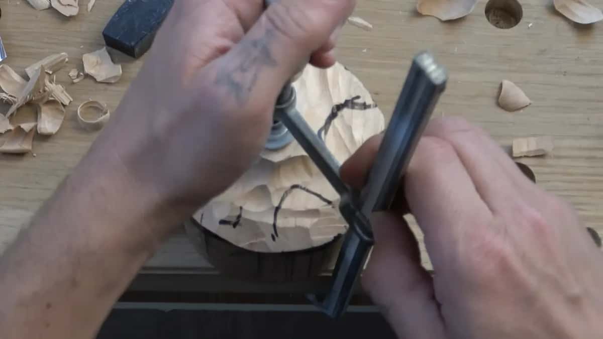 Both hands work the clamp over a top marked with black lines, chips scattered across the bench