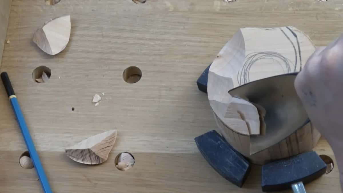 From above, a big gouge scoops a curved bite out of the top while a blue pencil lies on the bench