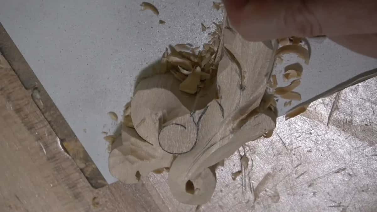 Hand above the scroll, its pencil circle still on the flat face