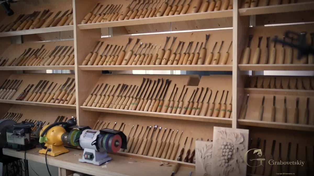 Shelves of gouges on the shop wall, with two bench grinders below them